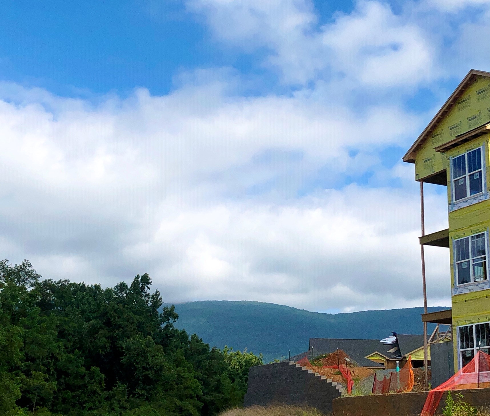 A yellow house with a red fence in front of a mountain.