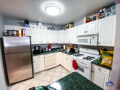 A kitchen with white cabinets and a stainless steel refrigerator.