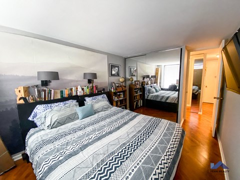 A bedroom with two beds and a bookshelf.