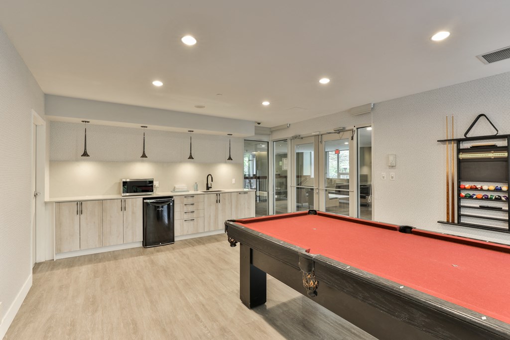a games room with a pool table and a kitchen
