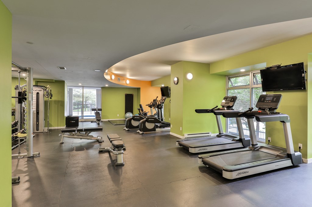 a gym with treadmills and weights and a tv