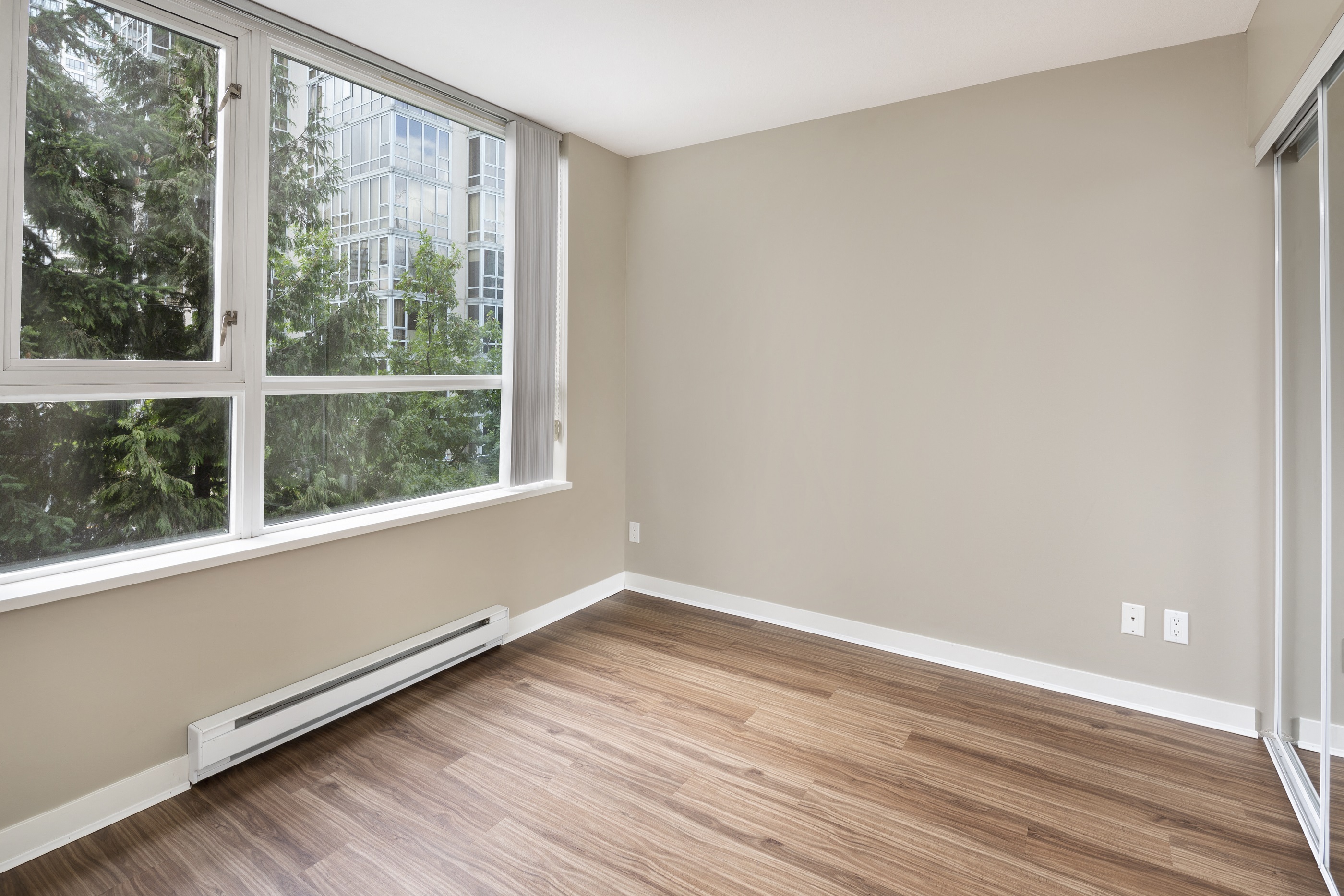 an empty room with wood flooring and large windows