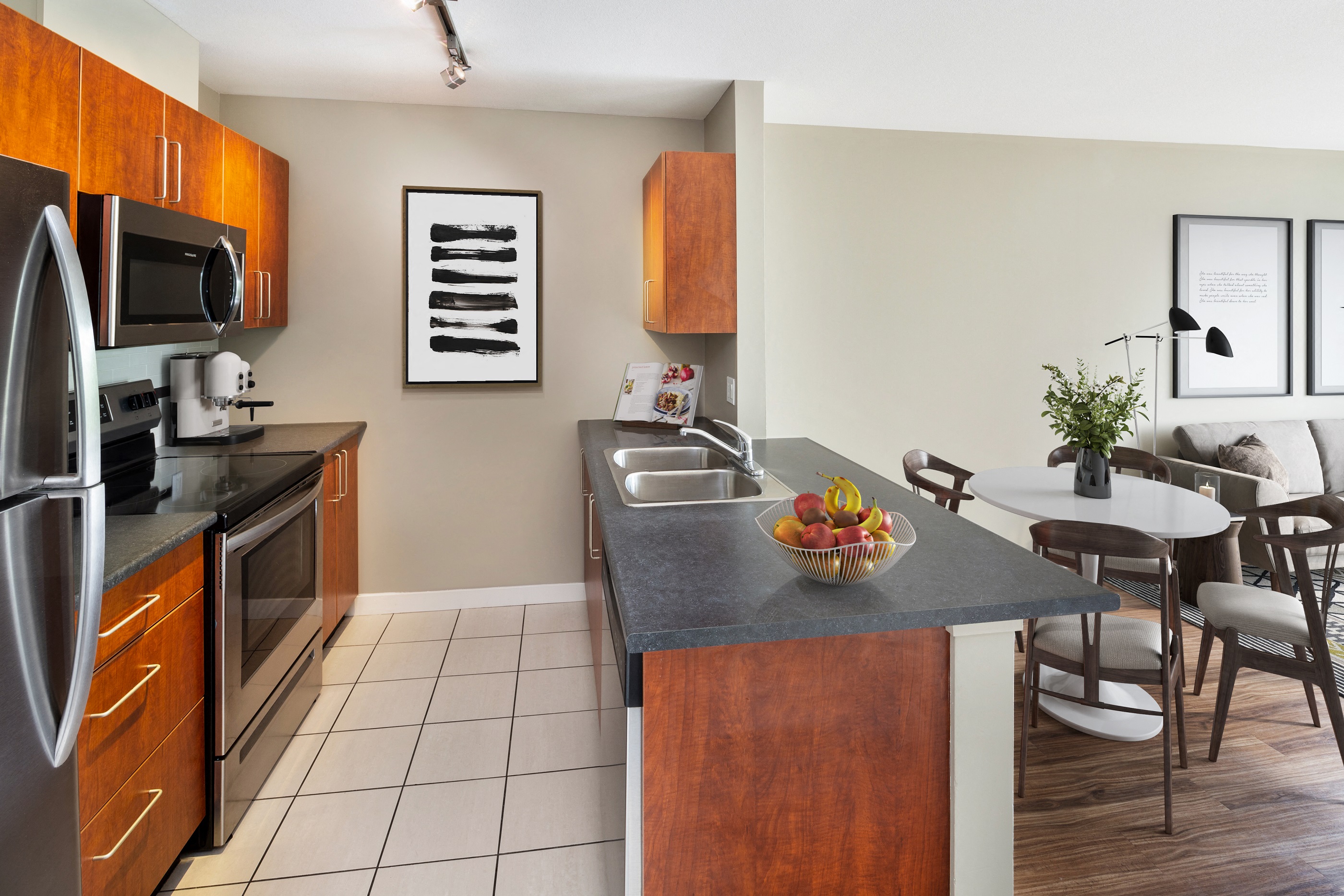 a kitchen with stainless steel appliances and a table with a bowl of fruit