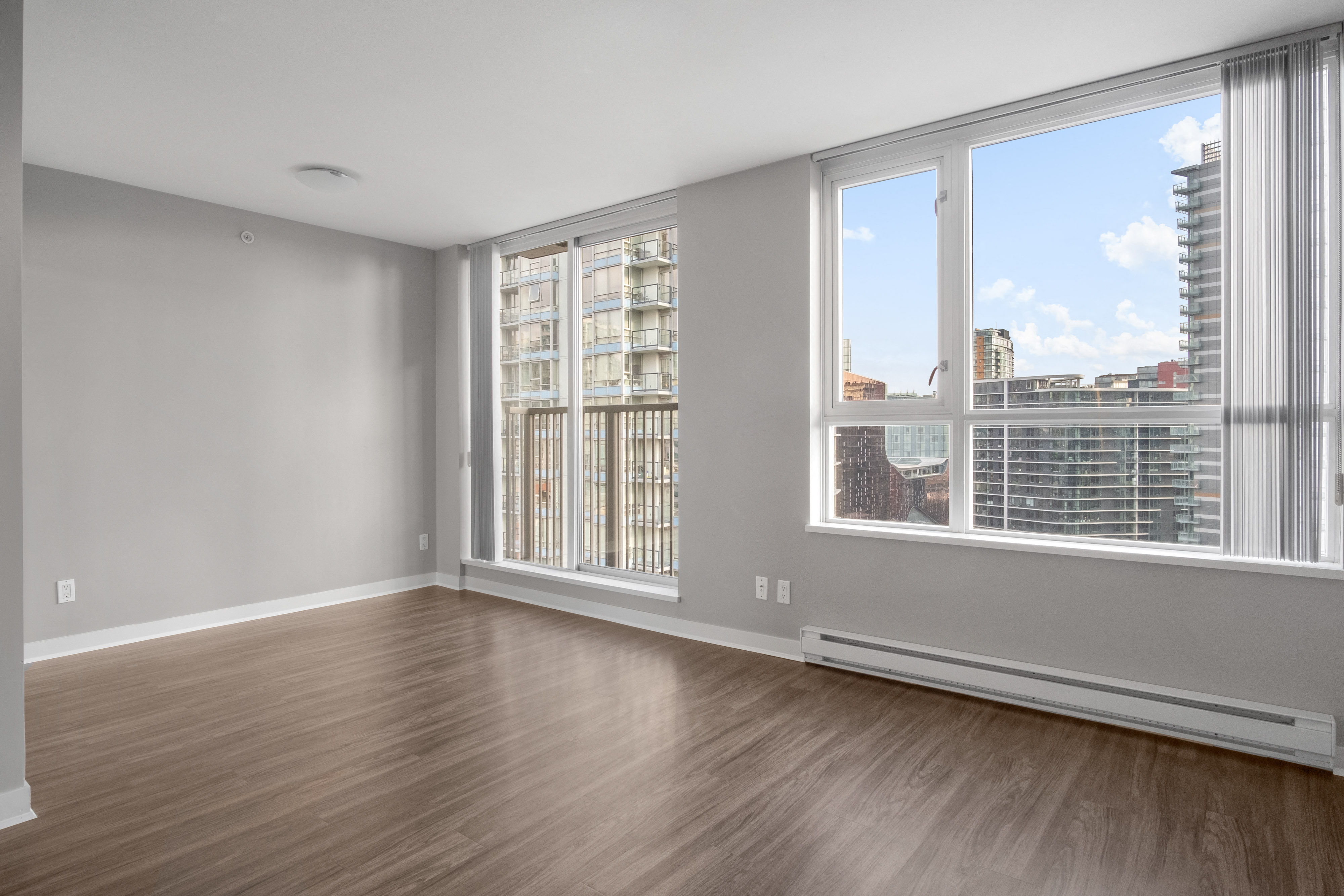 an empty living room with large windows and a city view