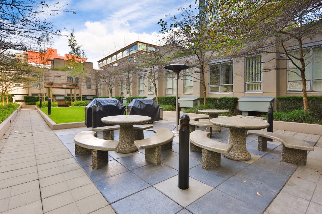 an outdoor seating area with benches and tables in front of a building