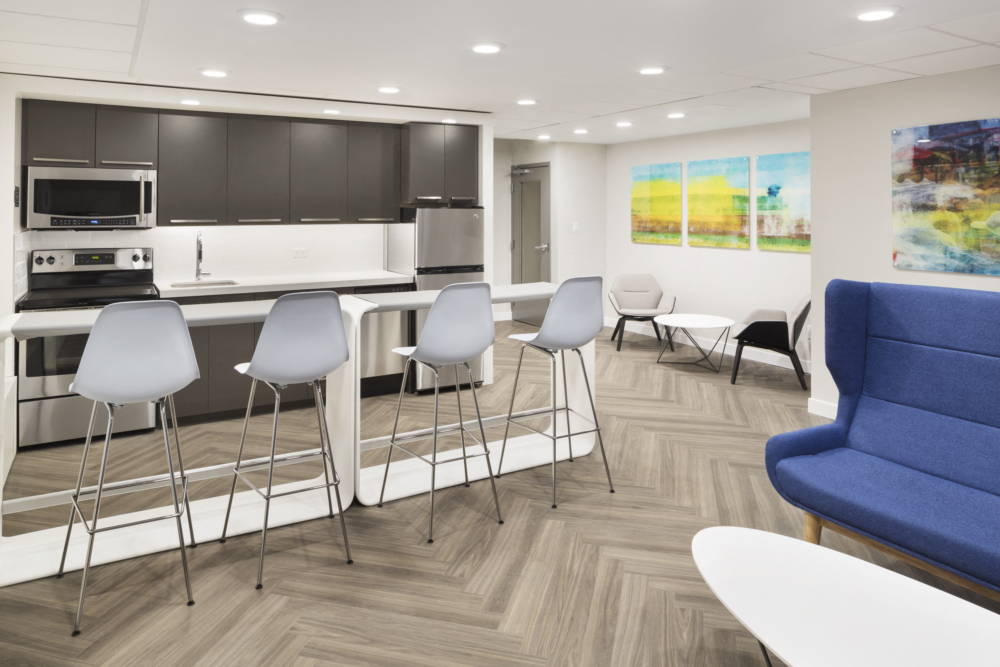 social room with a kitchen, bar stools and several seats