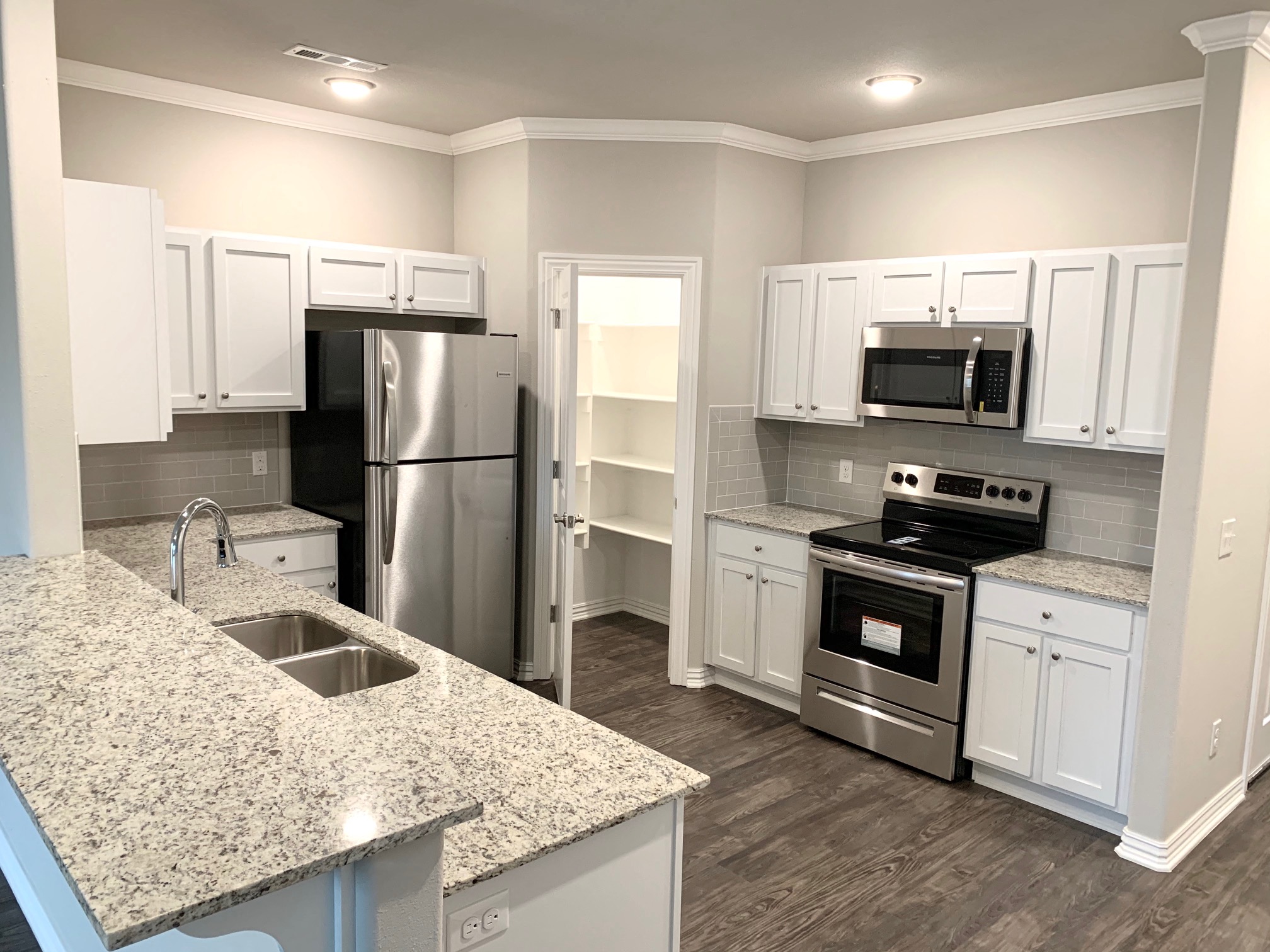 B1 (1-car) Kitchen with pantry with built-in shelving, granite countertops, stainless steel appliances