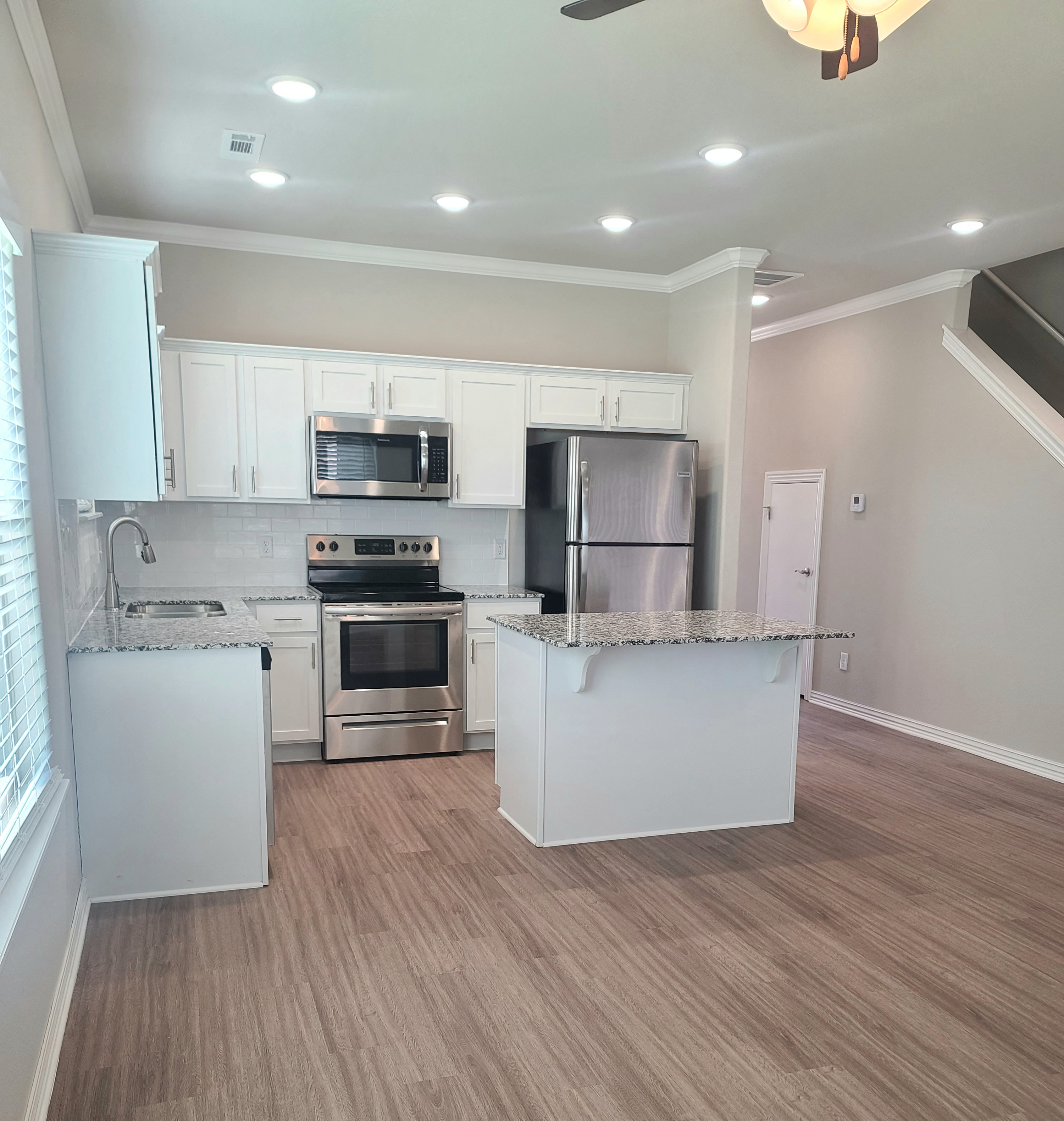 B4 Kitchen with laminate wood flooring, granite countertops, and stainless steel appliances