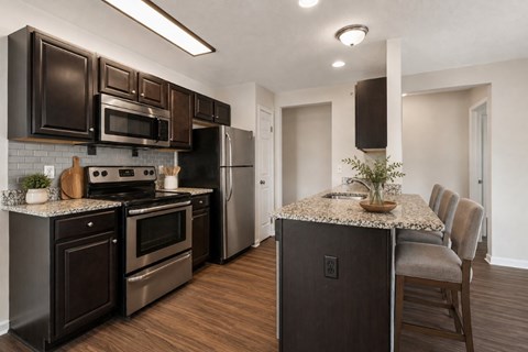A kitchen with dark brown cabinets and a granite countertop.
