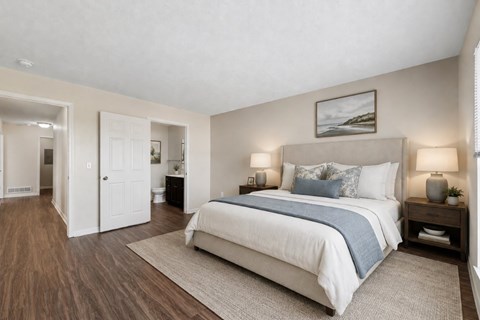 A bedroom with a large bed and a painting on the wall.