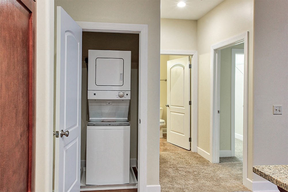 a laundry room with a washer and dryer and a door to a hallway