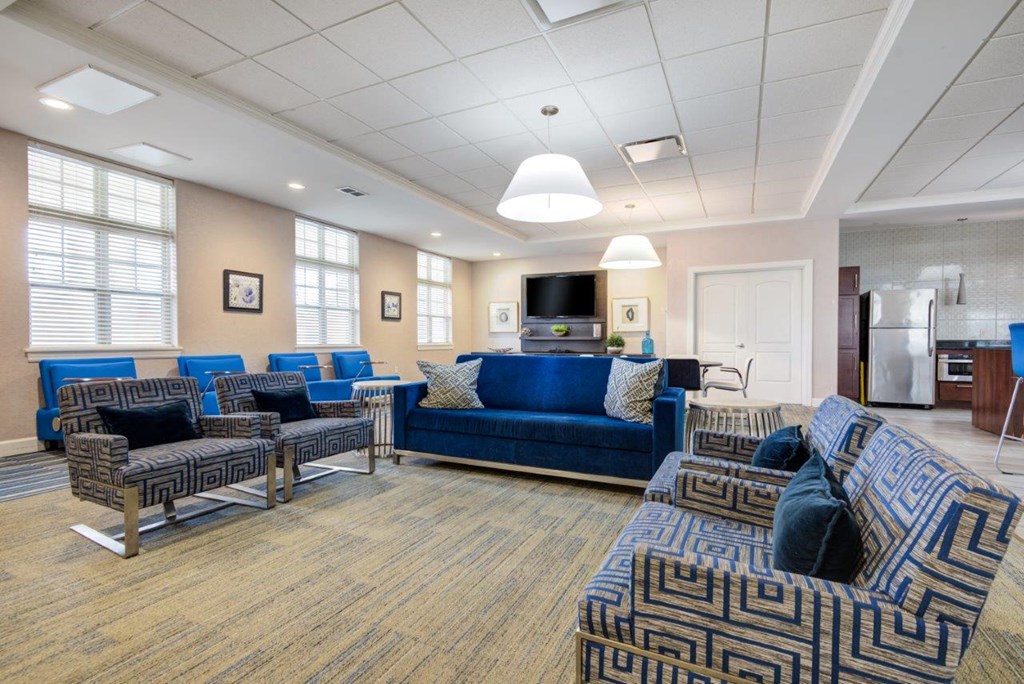a living room with blue couches and chairs and a kitchen
