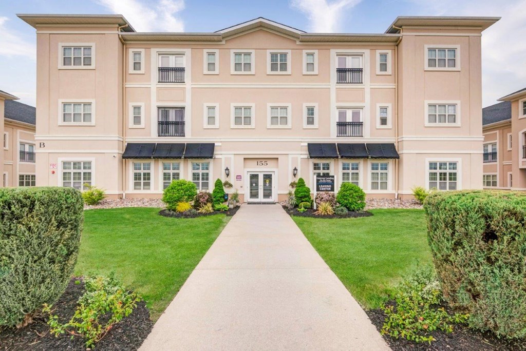 an exterior view of an apartment building with a walkway and lawn