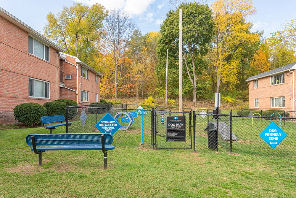 a park with a bench and a fence in front of an apartment building