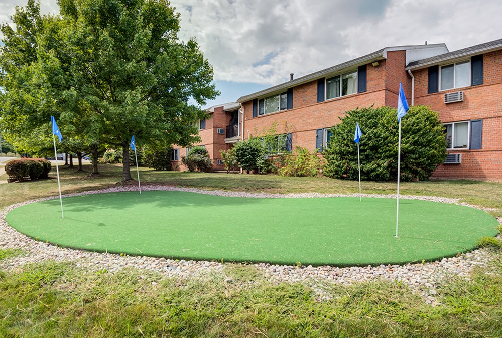 a putting green in front of a building with flags