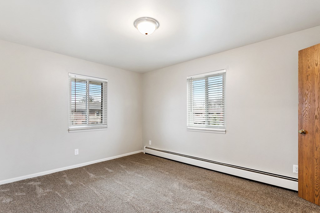 an empty room with carpet and two windows