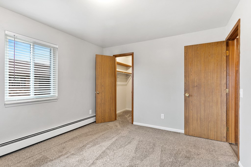 an empty bedroom with a closet and a door to a hallway