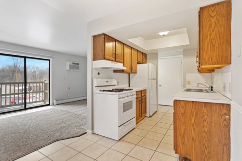 a kitchen with white appliances and wooden cabinets and a window
