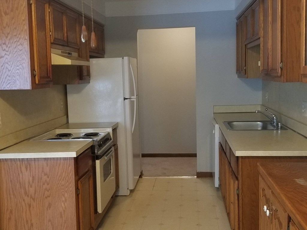 an empty kitchen with wooden cabinets and a white refrigerator