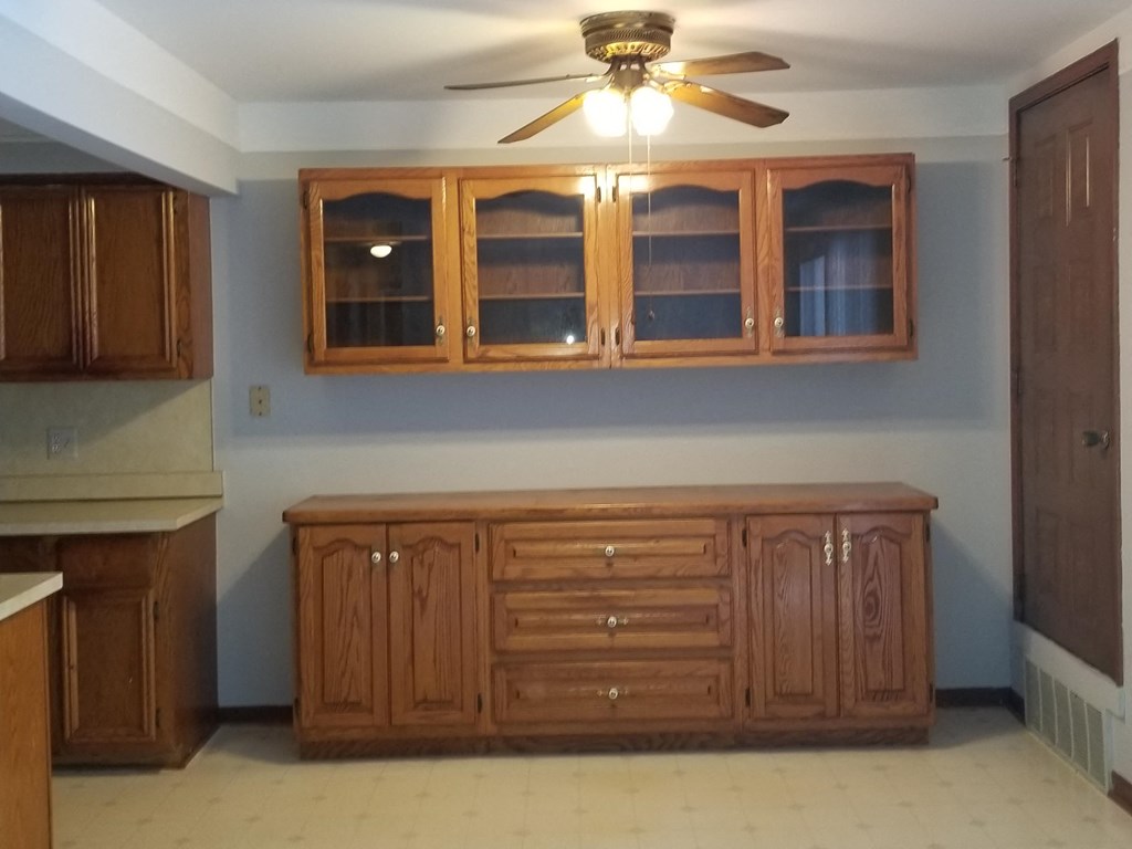 an empty kitchen with a large cabinet and a ceiling fan