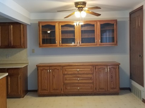 an empty kitchen with a large cabinet and a ceiling fan
