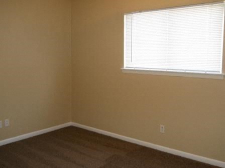 an empty room with a window and a wooden floor