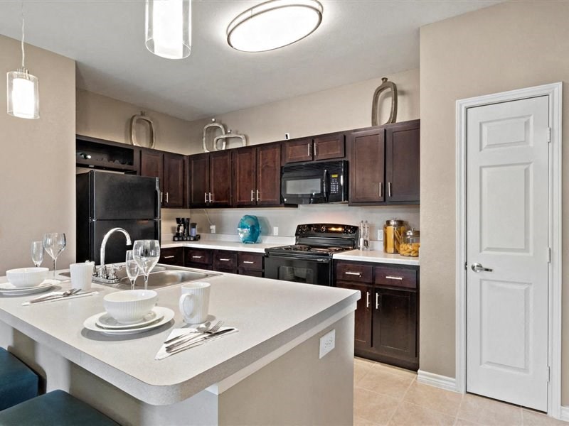 A kitchen with brown cabinets and black appliances.