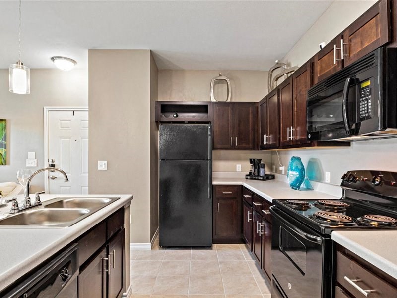 A kitchen with black appliances and brown cabinets.