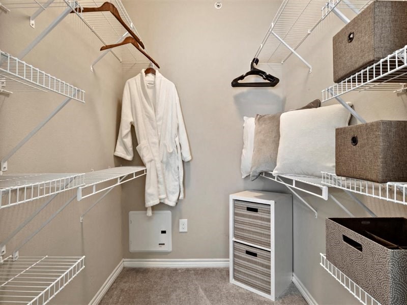 A white robe hanging on a rack in a walk-in closet.