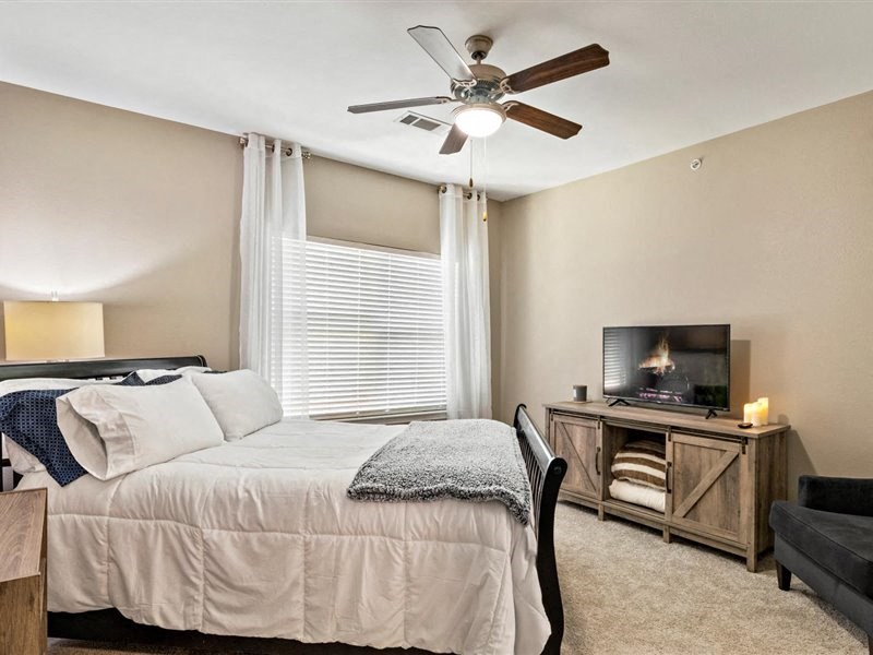A bedroom with a bed, a chair, and a television.