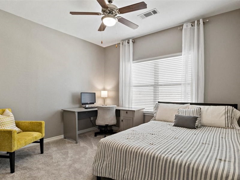 A bedroom with a bed, desk, chair, and window.