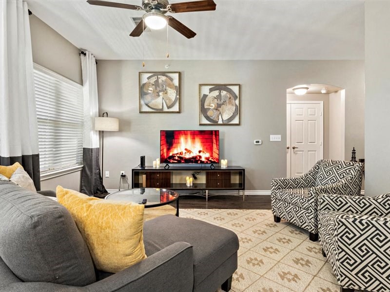 A living room with a grey couch, a fireplace, and a ceiling fan.