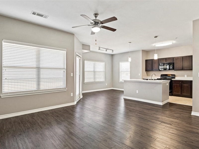 A spacious room with a ceiling fan and wooden flooring.
