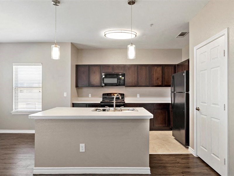 A kitchen with a white island and a black refrigerator.
