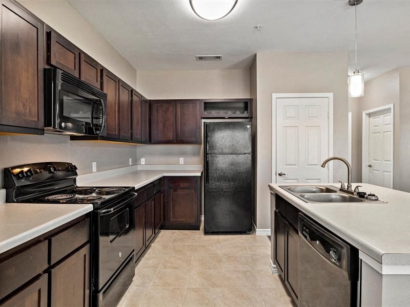 A kitchen with black appliances and brown cabinets.