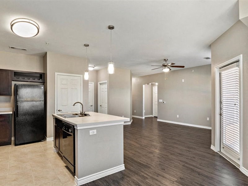 A kitchen with a black refrigerator and a white island.