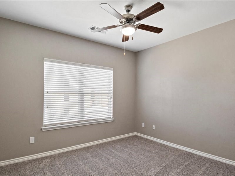 A room with a ceiling fan and a window with blinds.