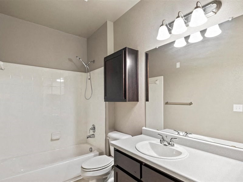 A white bathroom with a white toilet, sink, and a mirror.