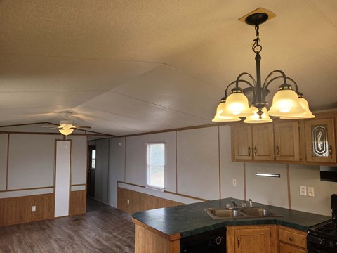 A kitchen with a black counter top and wooden cabinets.