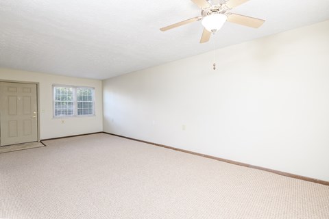 the living room of an empty house with a ceiling fan
