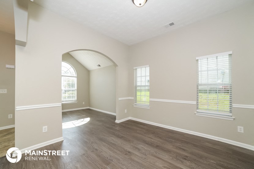 the spacious living room with hardwood flooring and an arched window