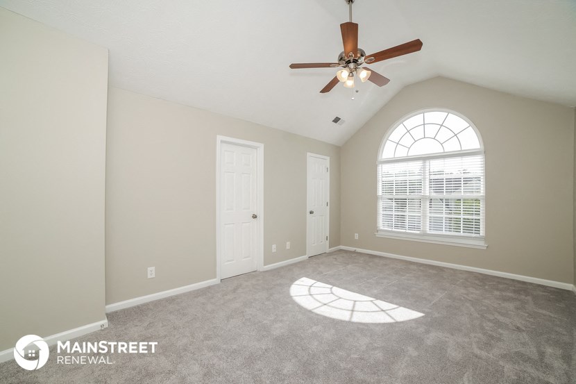 the spacious living room with ceiling fan and window