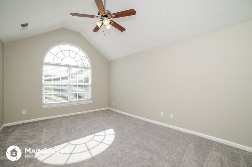 an empty room with a ceiling fan and a window