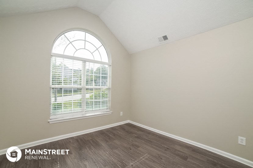 the spacious living room with wood flooring and a large window