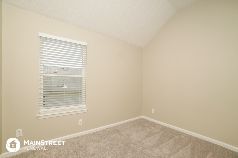 the upstairs bedroom has a carpeted floor and a window
