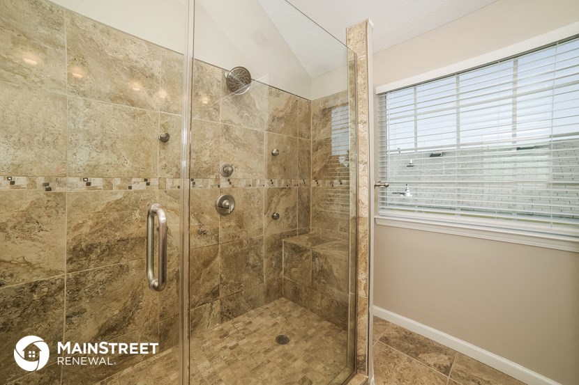 the master bathroom has a tiled shower and a window