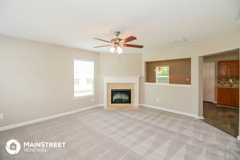 a living room with a fireplace and a ceiling fan