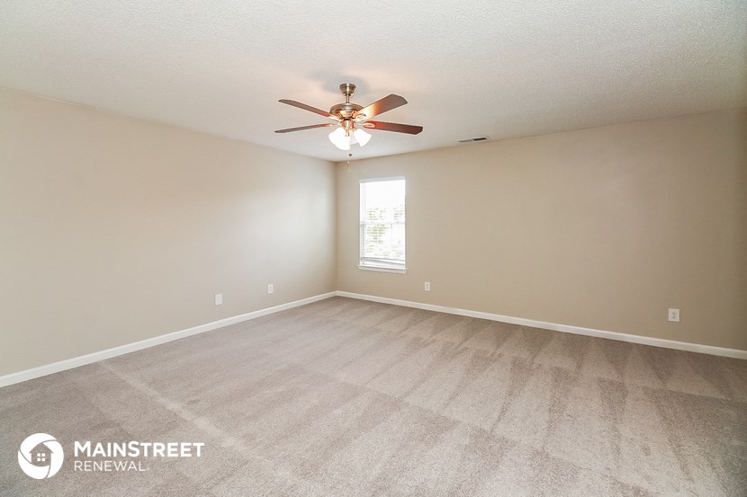 the spacious living room with carpeting and a ceiling fan