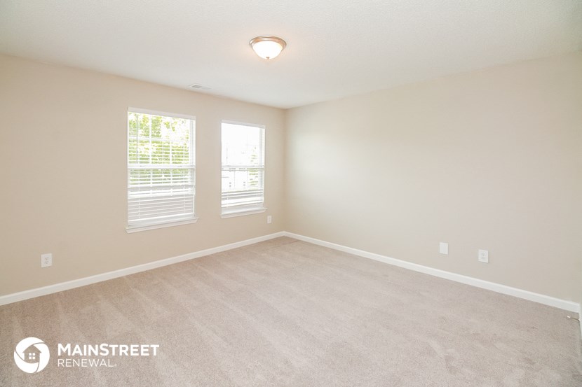 the spacious living room with carpeting and two windows