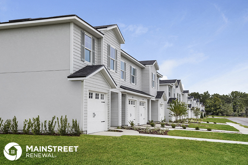 a row of town homes with white siding and green grass
